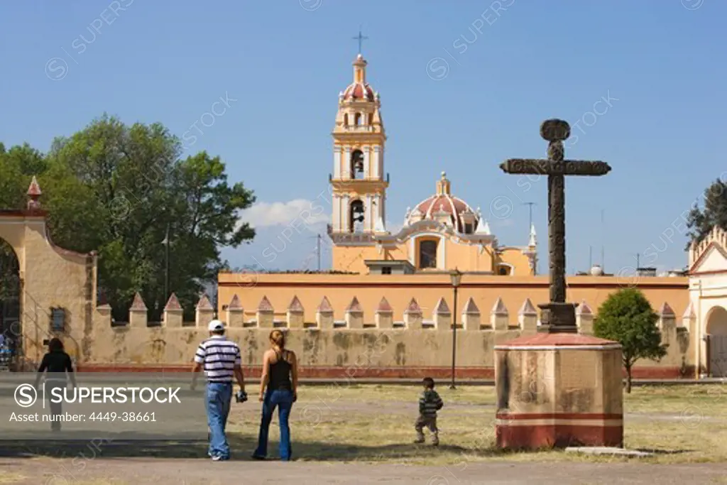 Family walking over the grounds of Ex-convento de San Gabriel in Cholula, the church of San Pedro is in the background, State of Puebla, Mexico