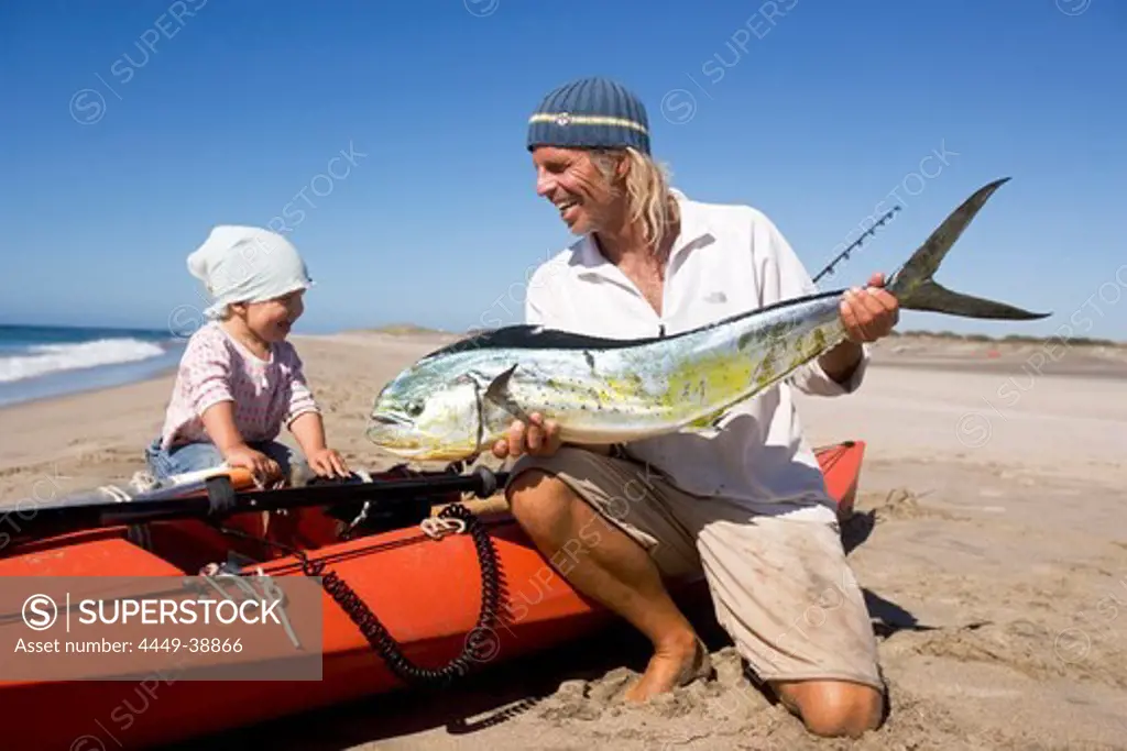 A man showing his little daughter his recently caught mahi-mahi, Punta Conejo, Baja California Sur, Mexico, America