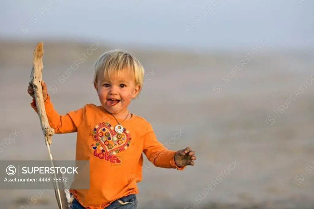 Little girl running with a stick in her hand over the sandy beach, Punta Conejo, Baja California Sur, Mexico, America