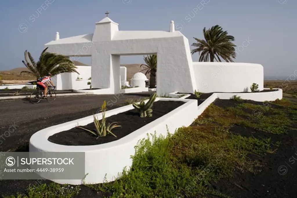 Cyclist, entrance to Costa Teguise by architect Cesar Manrique, UNESCO Biosphere Reserve, Lanzarote, Canary Islands, Spain, Europe