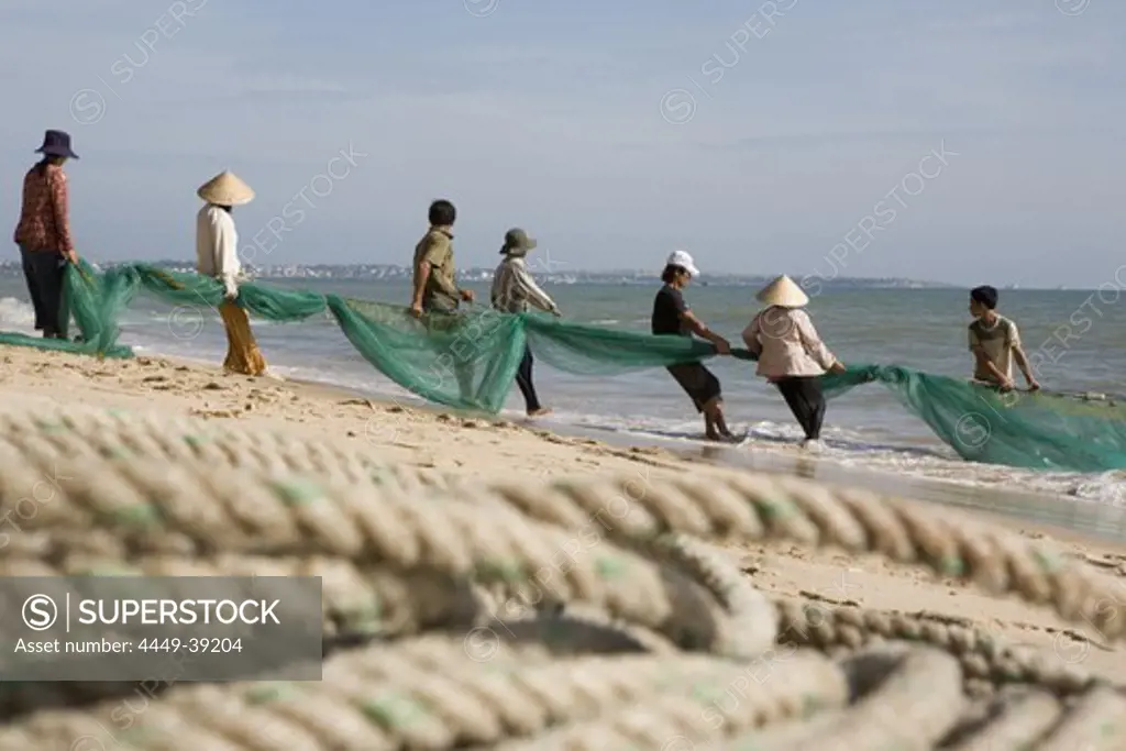 Fishermen with fishing net on the beach of Mui Ne, Binh Thuan Province, Asia