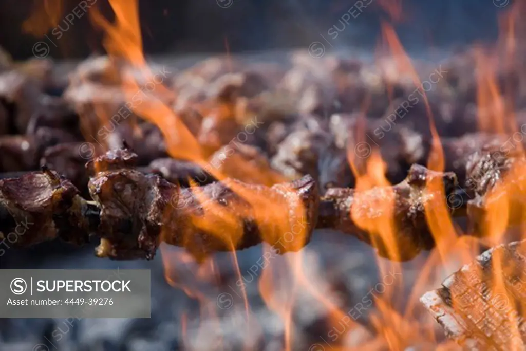 Grilling Espetada beef skewer kebabs over an open fire at a religiois festival, Ponta Delgada, Madeira, Portugal