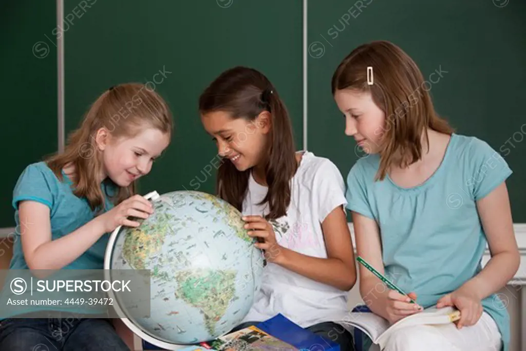 Schoolgirls with globe in classroom, Hamburg, Germany
