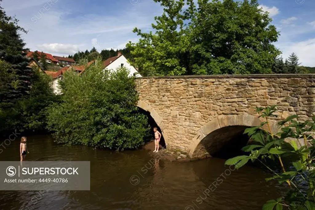 Children bathing in river near old stone bridge, Lauterecken, Rhineland-Palatinate, Germany