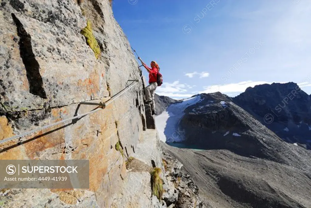 Woman climbing fixed rope route through Tschenglser Hochwand, Ortler range, Trentino-Alto Adige/South Tyrol, Italy