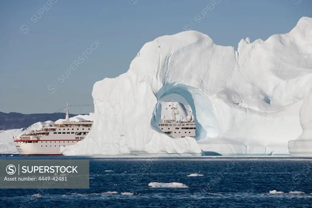 Cruise ship MS Deutschland and iceberg with hole from Ilulissat Kangerlua Icefjord, Ilulissat (Jakobshavn), Disko Bay, Kitaa, Greenland