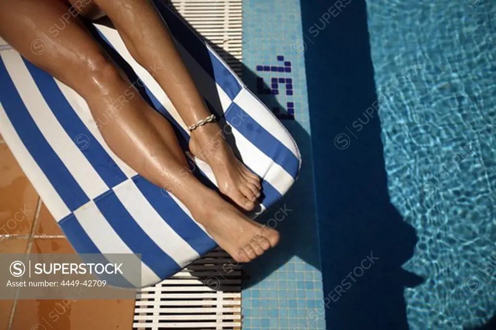 Womans' legs on a sunlounger by the pool
