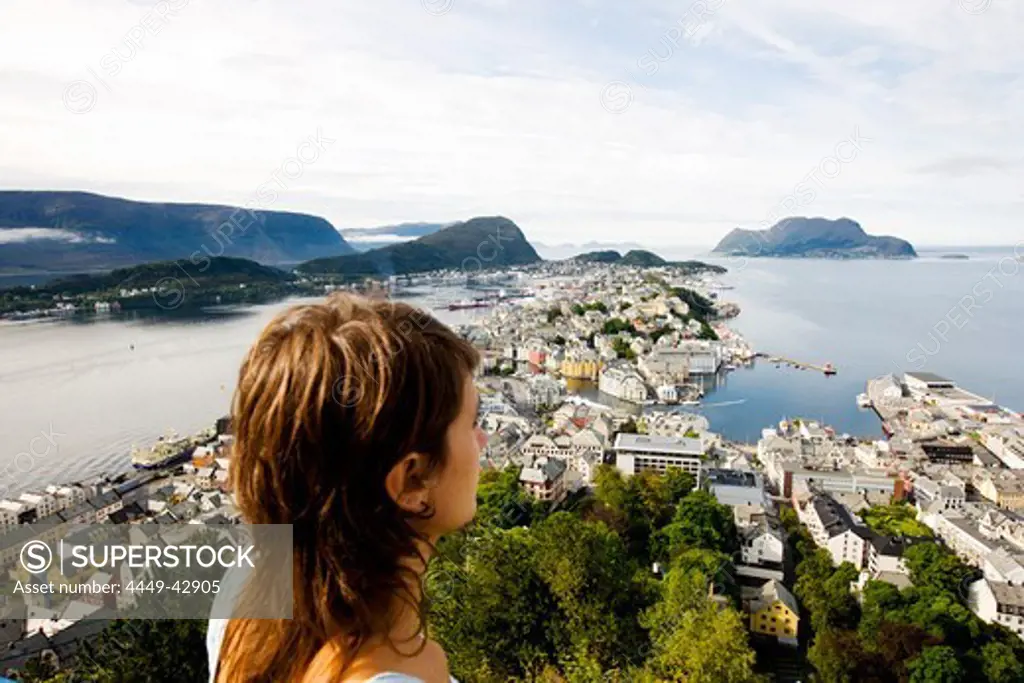 Young woman looking at the town Alesund under clouded sky, More og Romsdal, Norway, Scandinavia, Europe