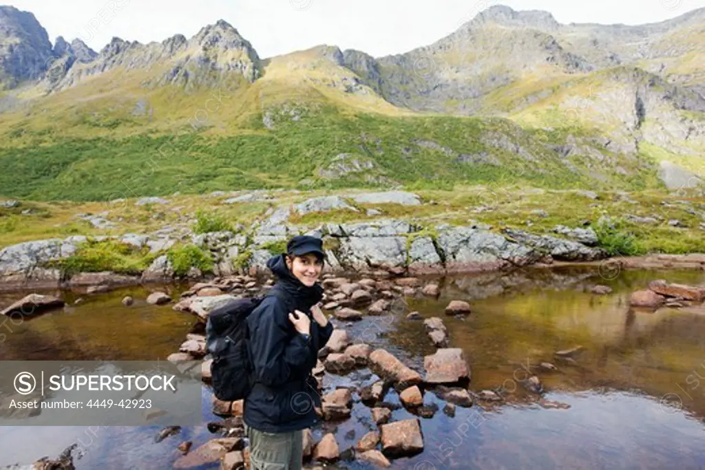 Young woman at the shore of a lake in the mountains, Lofoten, Norway, Scandinavia, Europe