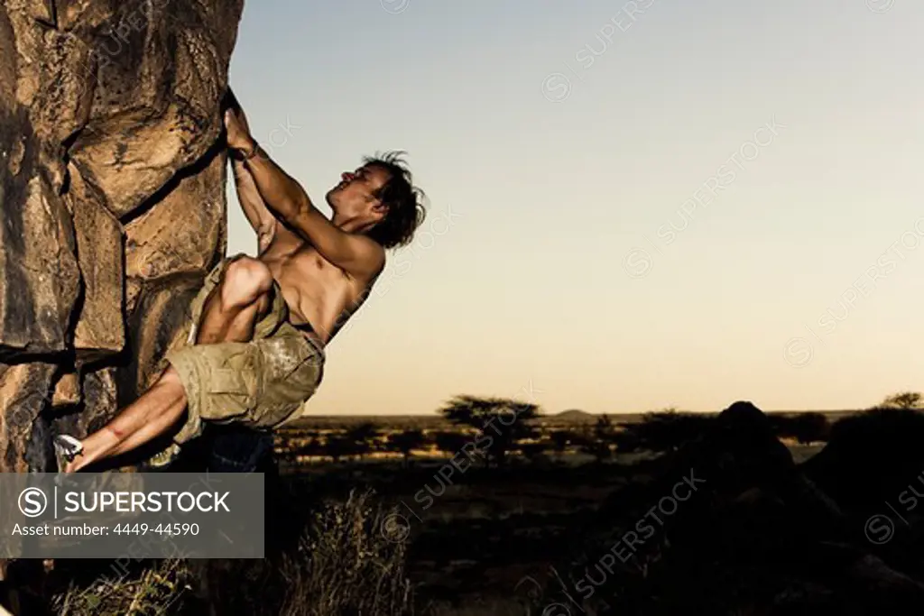 Young man bouldering in the evening sun, Hand of Fatima, Hombori, Mali, Africa