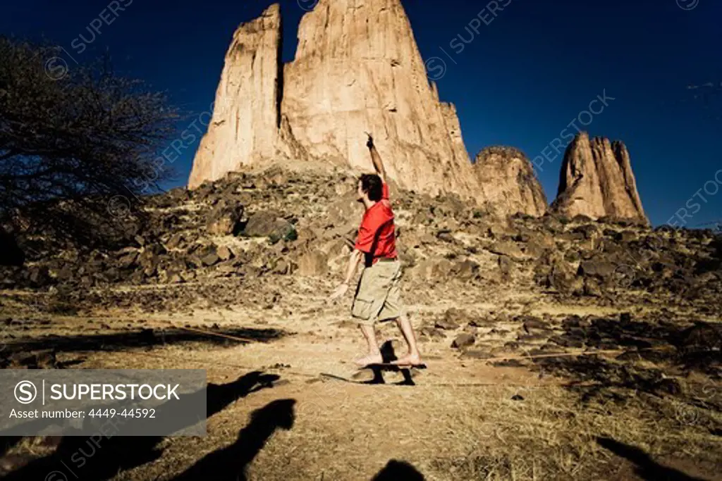 Young man balancing on slackline, Hand of Fatima in the background, Hombori, Mali, Africa