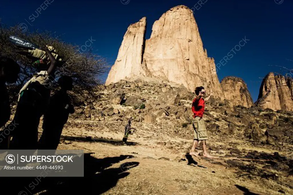 Young man balancing on slackline, African people watching, Hand of Fatima in the background, Hombori, Mali, Africa