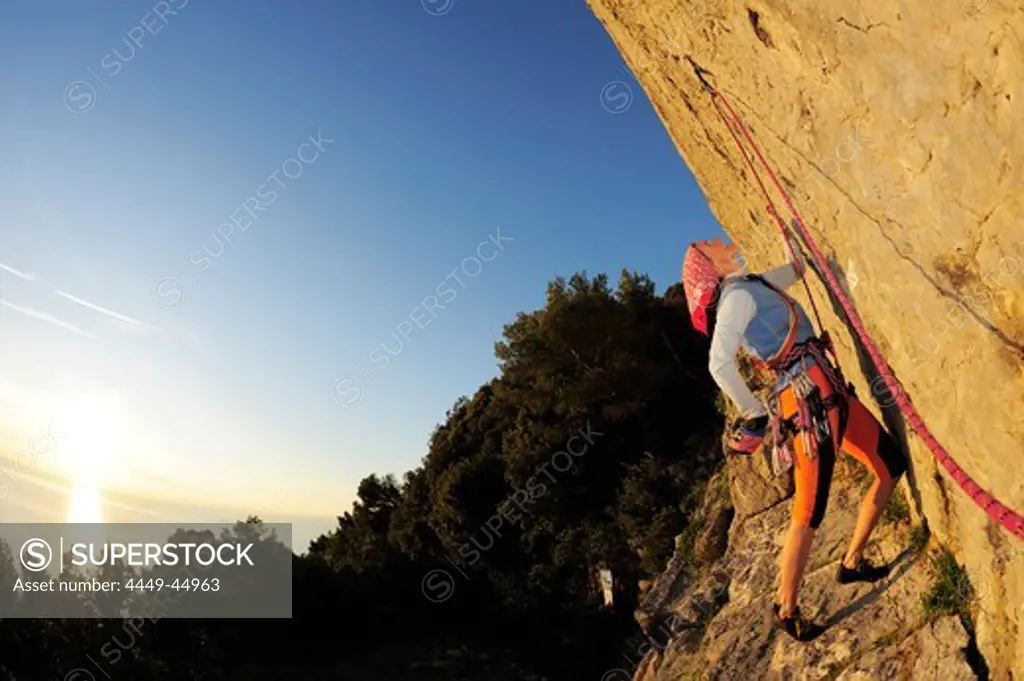 Woman climbing an overhanging rock face above the Mediterranean sea, natural park Porto Venere, national park Cinque Terre, UNESCO world heritage site, Liguria, Italy