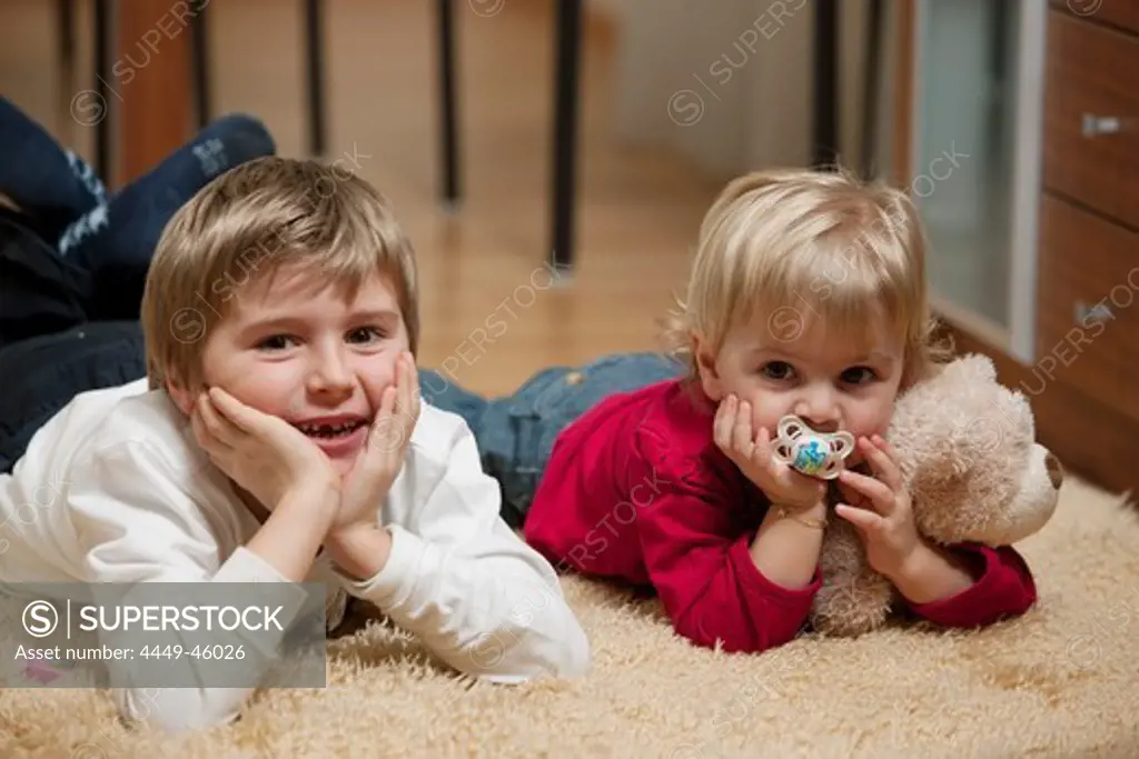 Boy (6 years) and girl (2 years) lying on carpet