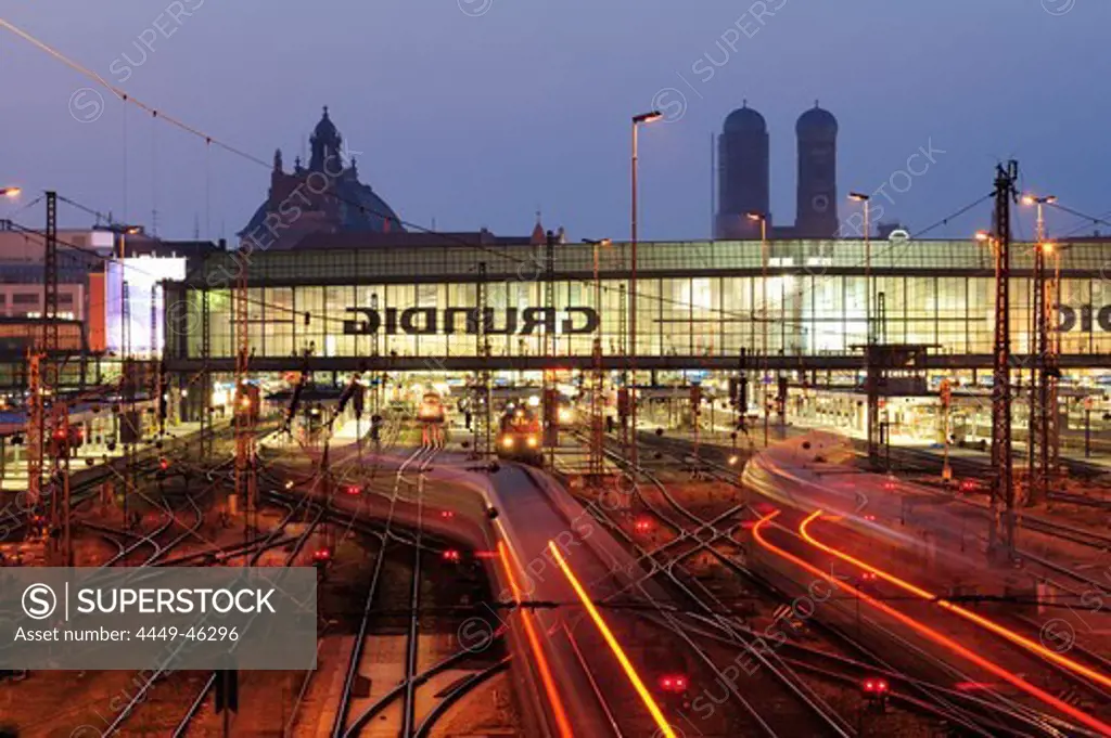 Illuminated tracks and railway building, twin towers of the Frauenkirche cathedral and palace of justice in the background, Munich main station, Munich, Upper Bavaria, Bavaria, Germany