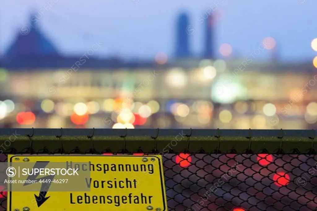 High voltage sign, Munich main station and the twin towers of the Frauenkirche cathedral out of focus in the background, Munich, Upper Bavaria, Bavaria, Germany