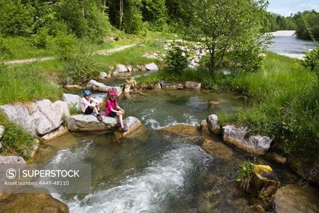 Two girls sitting on rocks in river Isar, Isar renaturation, fish-ladder near Bad Toelz, Isar Cycle Route, Upper Bavaria, Germany