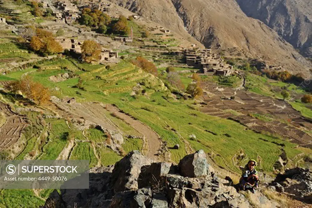 Girl and village amidst fields in Ourika valley, trekking in the High Atlas from Imlil, Toubkal Area, Morocco