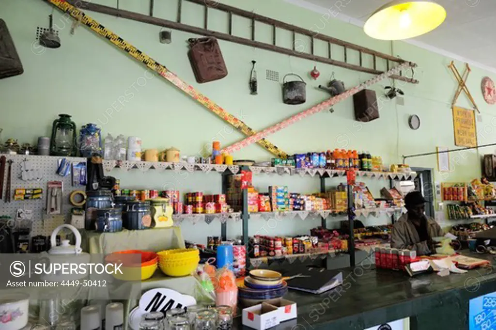 Salesman standing at counter, racks with products in background, shop in Solitaire, Solitaire, near Namib Naucluft National Park, Namib desert, Namibia