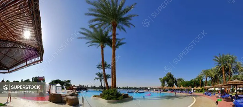 panorama of swimming-pool area with palm trees and view to the Nile and western bank of Nile, Crocodile Island, Luxor, Egypt, Africa