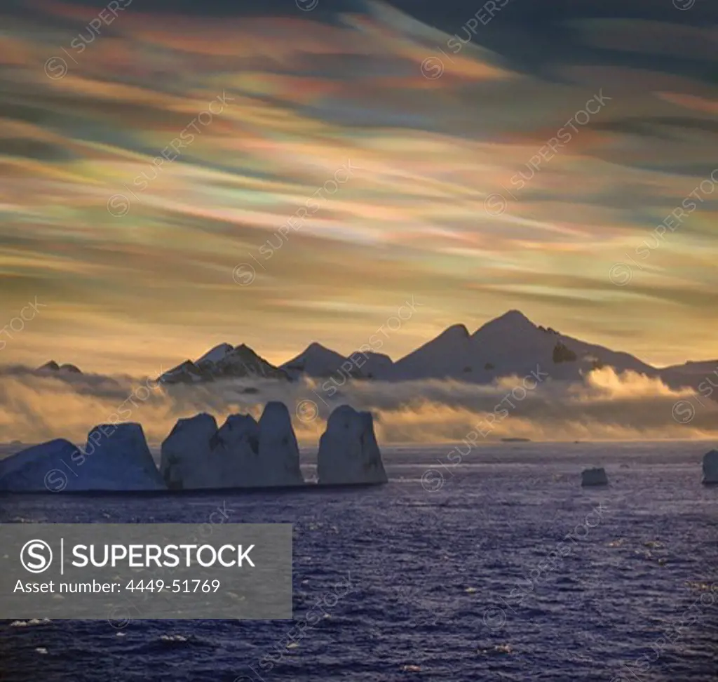 Mother of pearl clouds, nacreous clouds over snow covered iceberg, Antarctic Peninsula, Antarctica