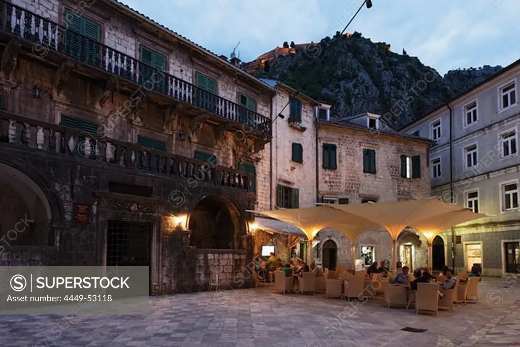 Restaurant at a square in the evening, in the background fortress on a hill, Kotor, Montenegro, Europe