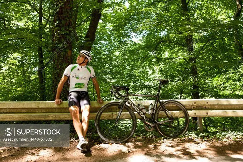 Bicycle racer leaning against guardrail, Bergisches Land, North Rhine-Westphalia, Germany