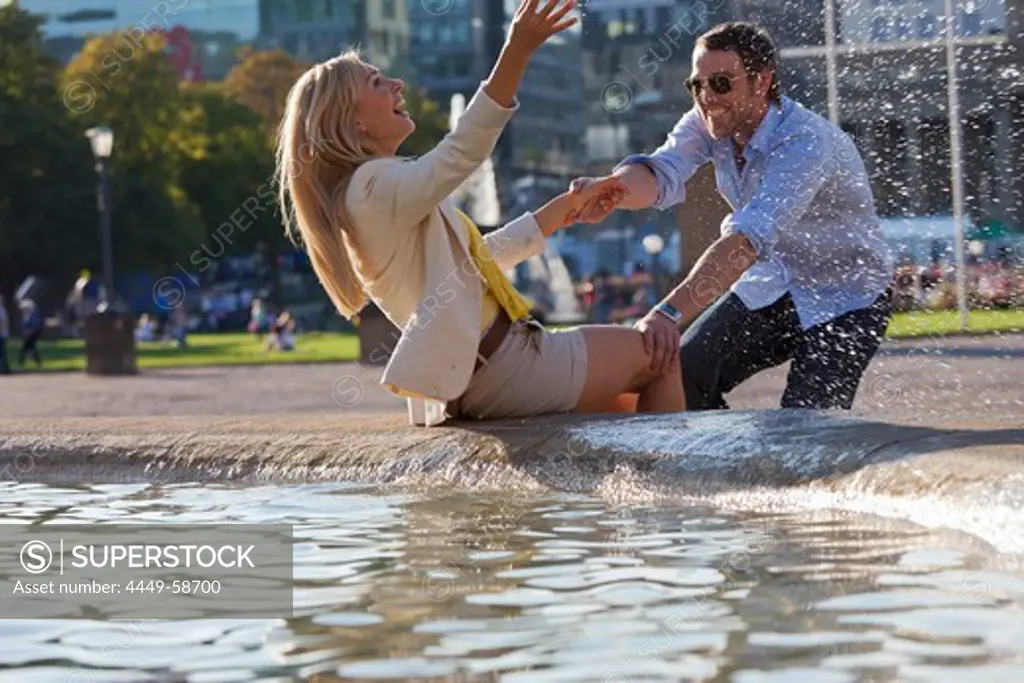 Young couple enjoying the fountain on Schlossplatz, New Castle, Stuttgart, Baden Wurttemberg, Germany