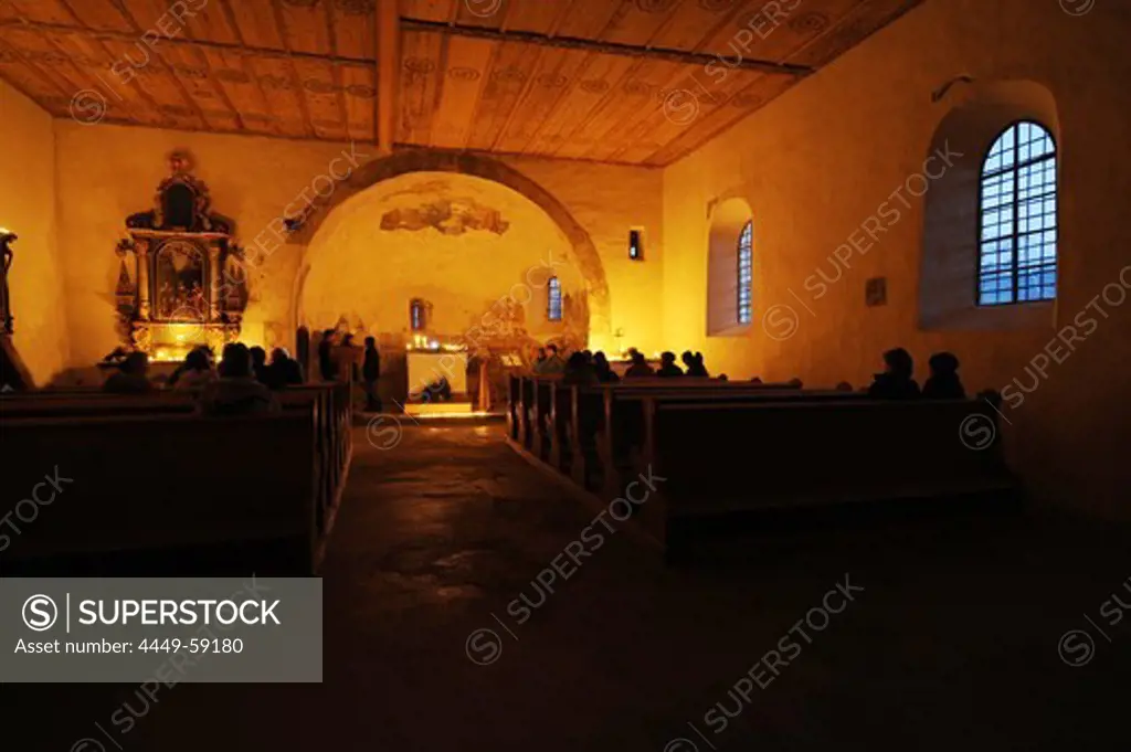 People inside of the romanic church St. Vitus at candle light, Tartsch, Mals, Vinschgau, South Tyrol, Alto Adige, Italy, Europe