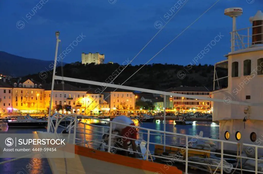 Boat entering the harbour of Senji at night, Senj castle in the background, near Velebit, Adria, Croatia