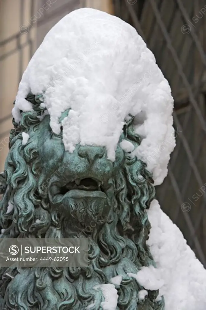 Snow covered lion sculpture in front of entrance of the Residenz palace, Munich, Bavaria, Germany
