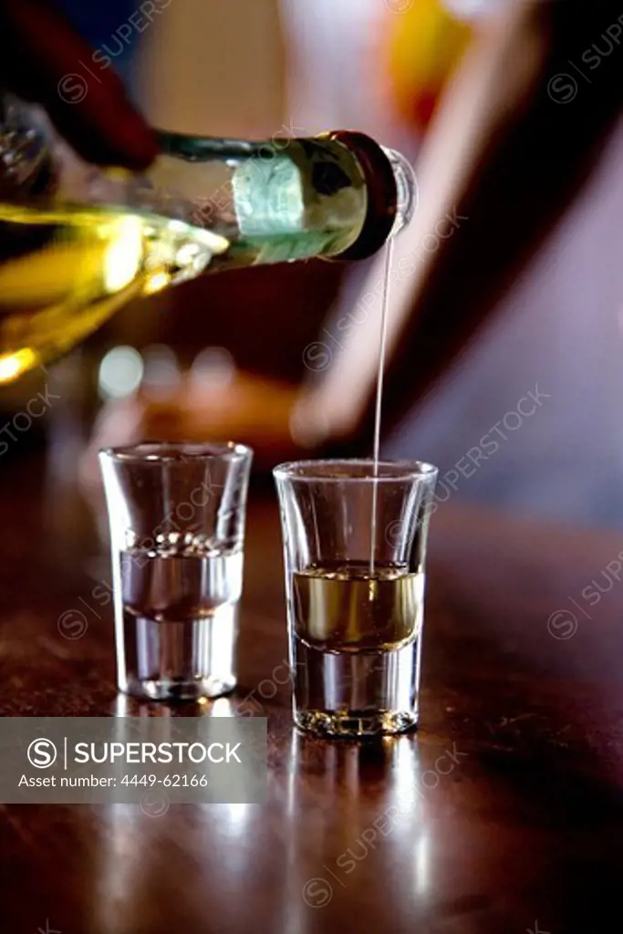 Person pouring Grappa into two glasses, Nardini Grappa Bar, Bassano del Grappa, Veneto, Italy