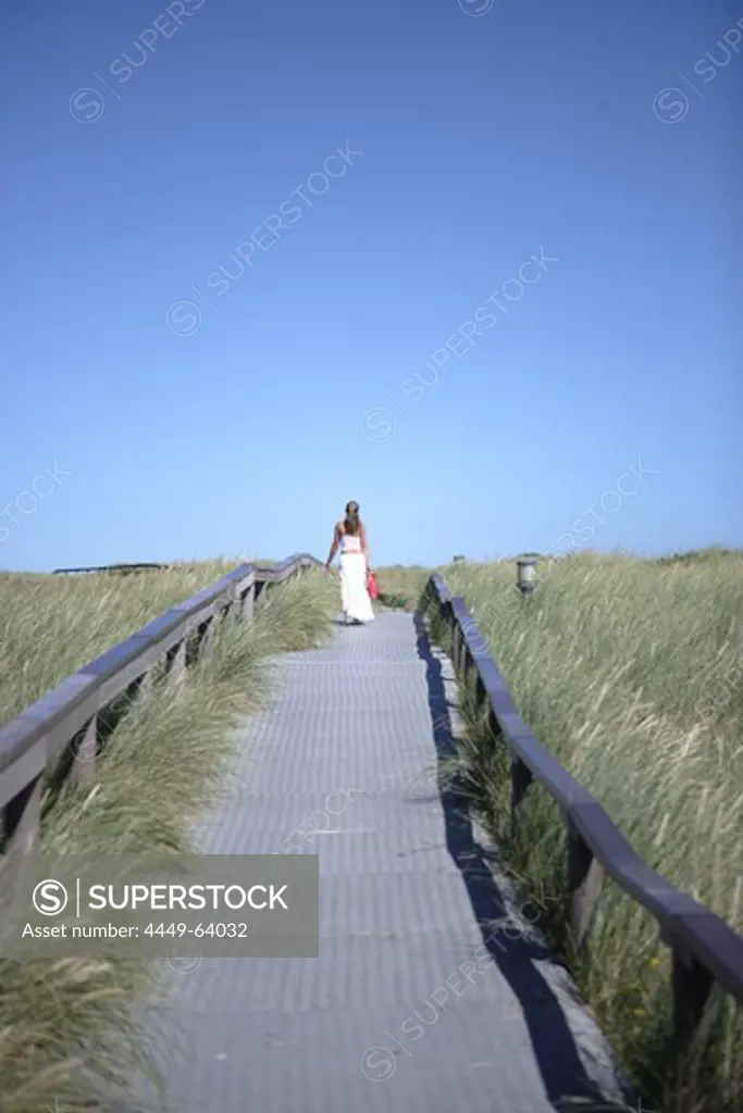 Woman walking over path between dunes, Wenningstedt, Sylt, Schleswig-Holstein, Germany
