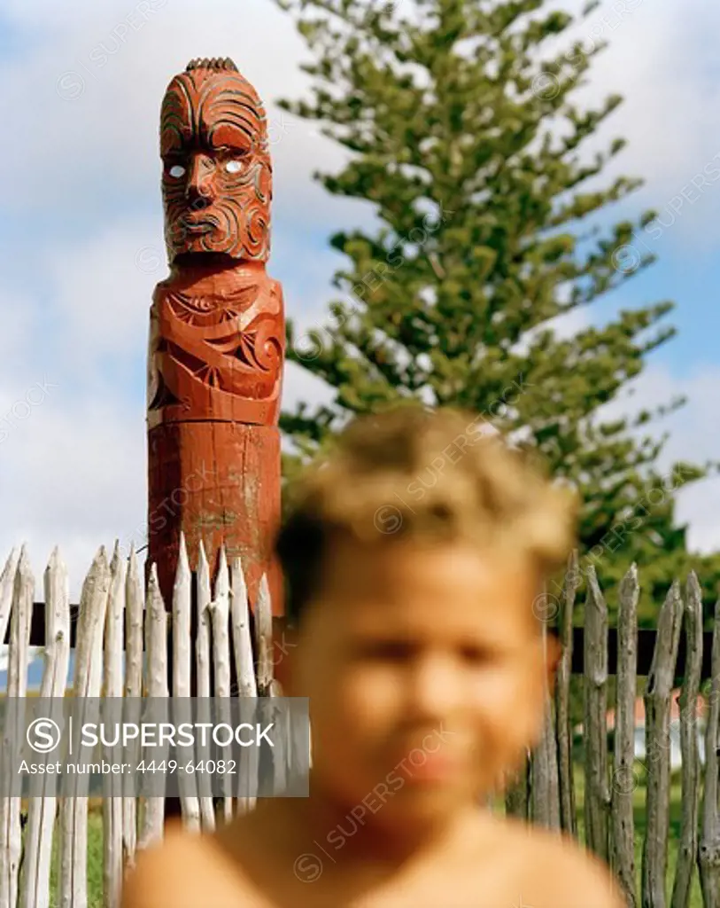A Maori boy and a carved figure at school entrance, Torere, North coast, Eastcape, North Island, New Zealand