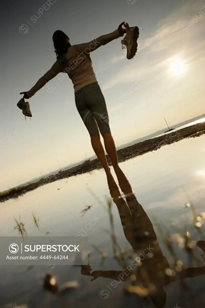 Barefoot female jogger standing at lake Starnberg, Ambach, Bavaria, Germany