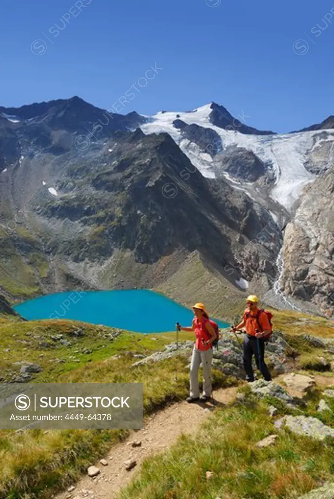 couple hiking above lake Gruenausee, Wilder Freiger and galcier Wiilder-Freiger-Ferner in background, Stubaier Alpen range, Stubai, Tyrol, Austria