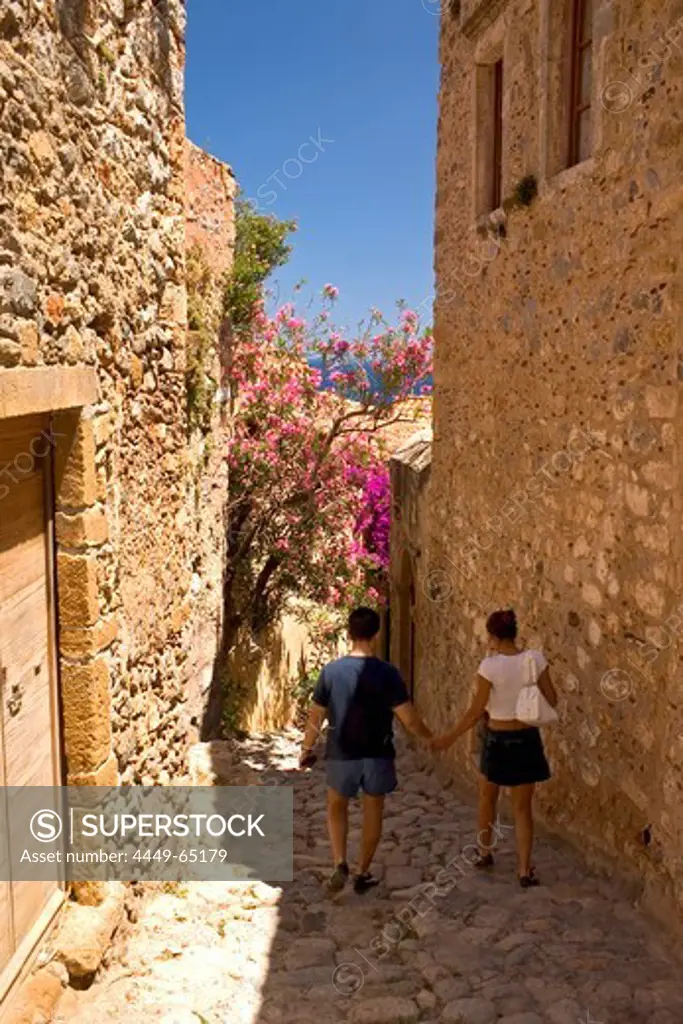 Couple walking down an alley in the medieval village of Monemvasia, Lakonia, Peloponnese, Greece