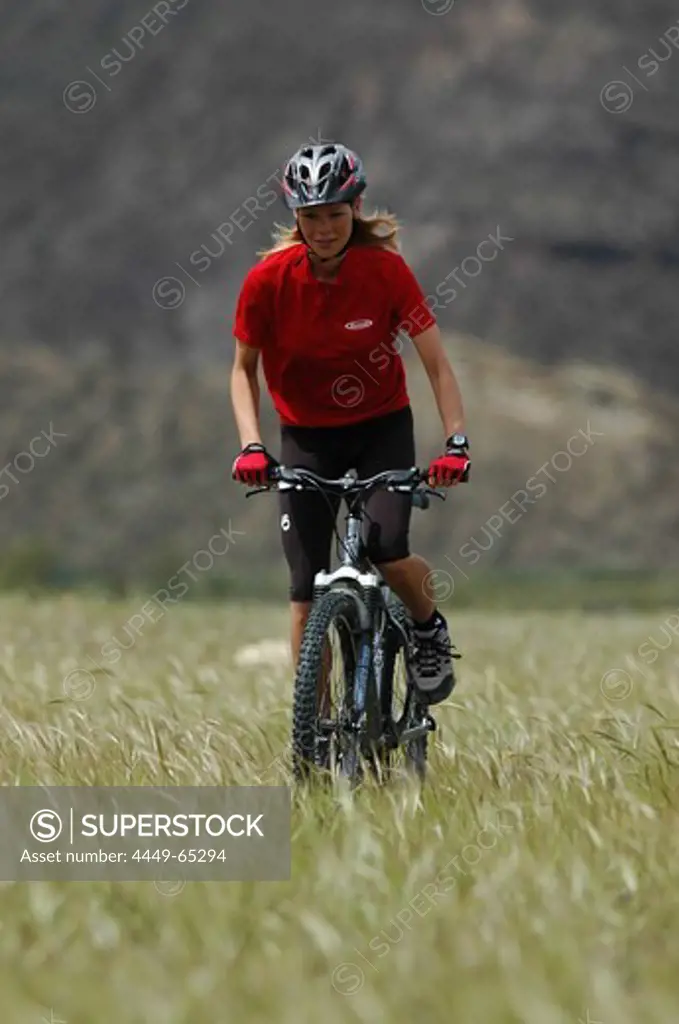 Woman on a mountainbike tour, riding through a field, Andalusia, Spain