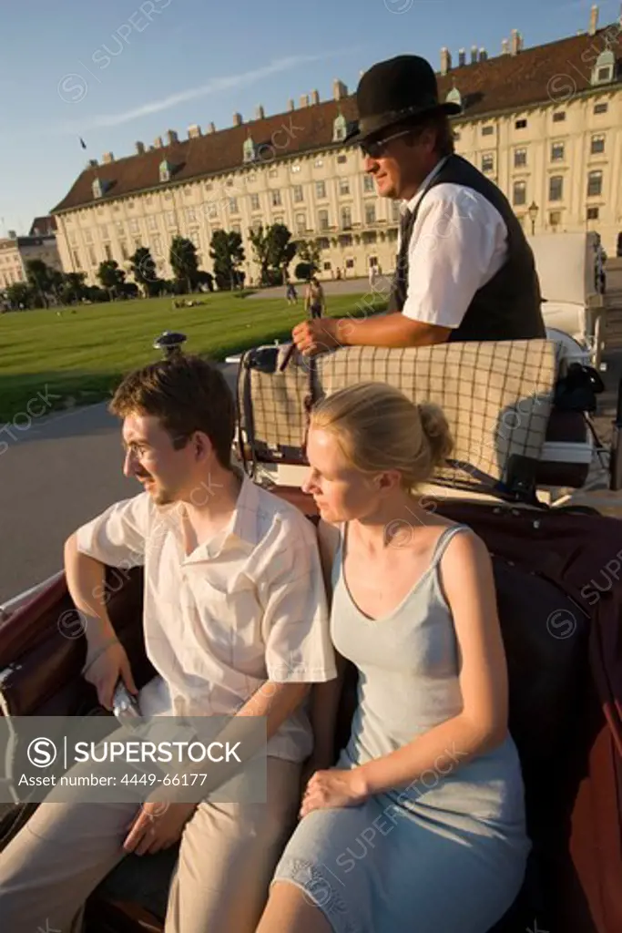 Fiaker coachman showing tourists Neue Hofburg during a city tour, Vienna, Austria