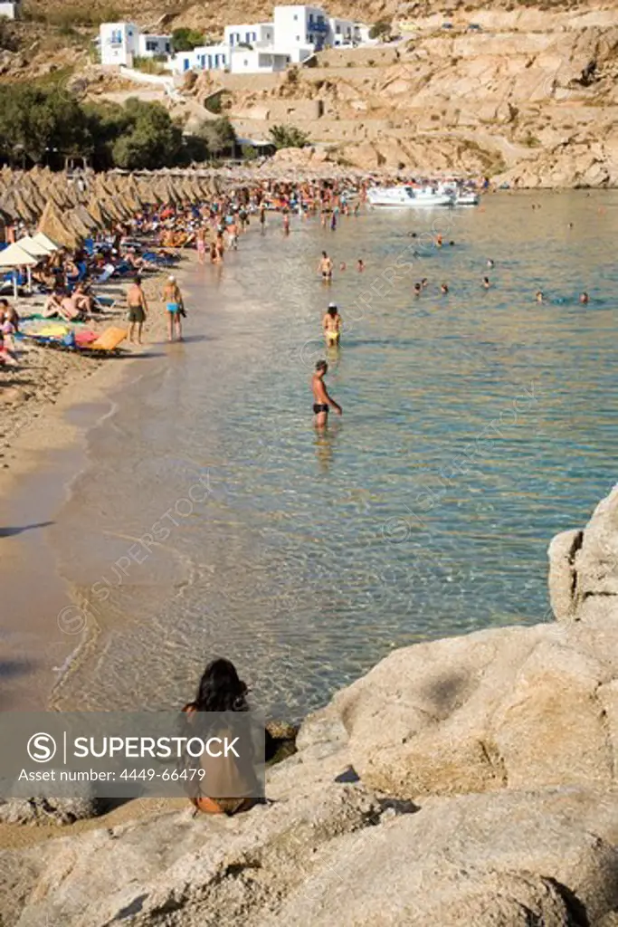 View from a woman sitting on a rock to bathing people at Super Paradise Beach, knowing as a centrum of gays and nudism, Psarou, Mykonos, Greece
