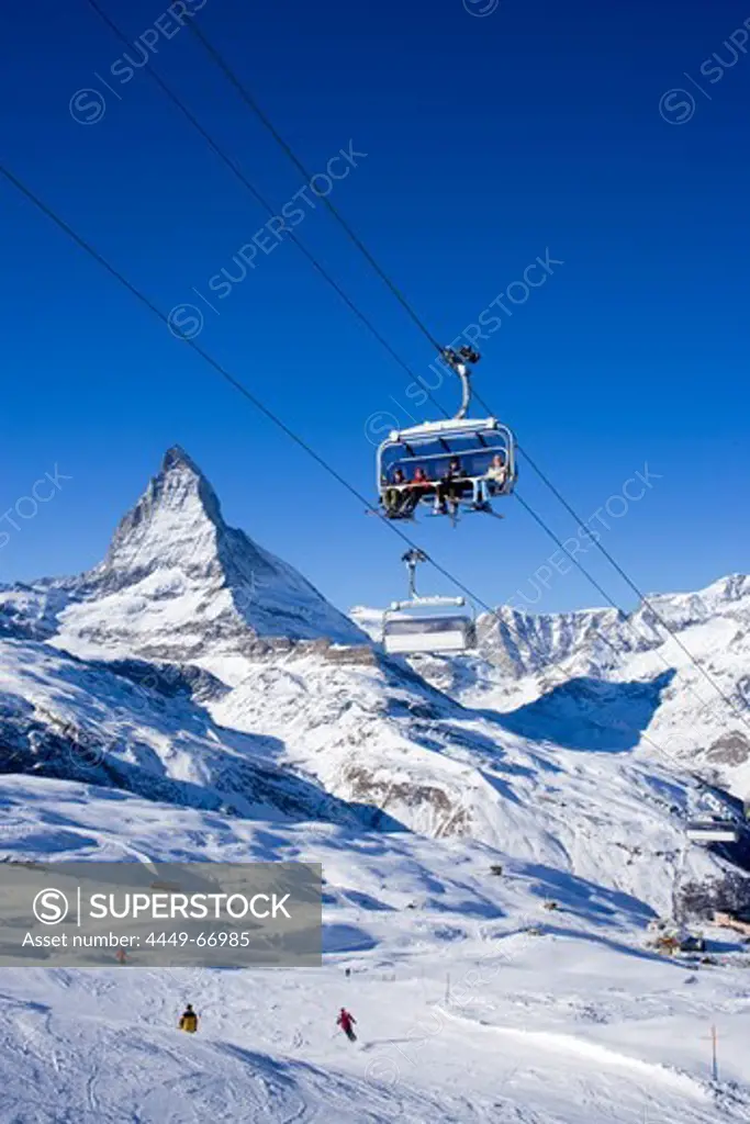 Skiers sitting on a ski lift, Matterhorn (4478 m) in background, Zermatt, Valais, Switzerland