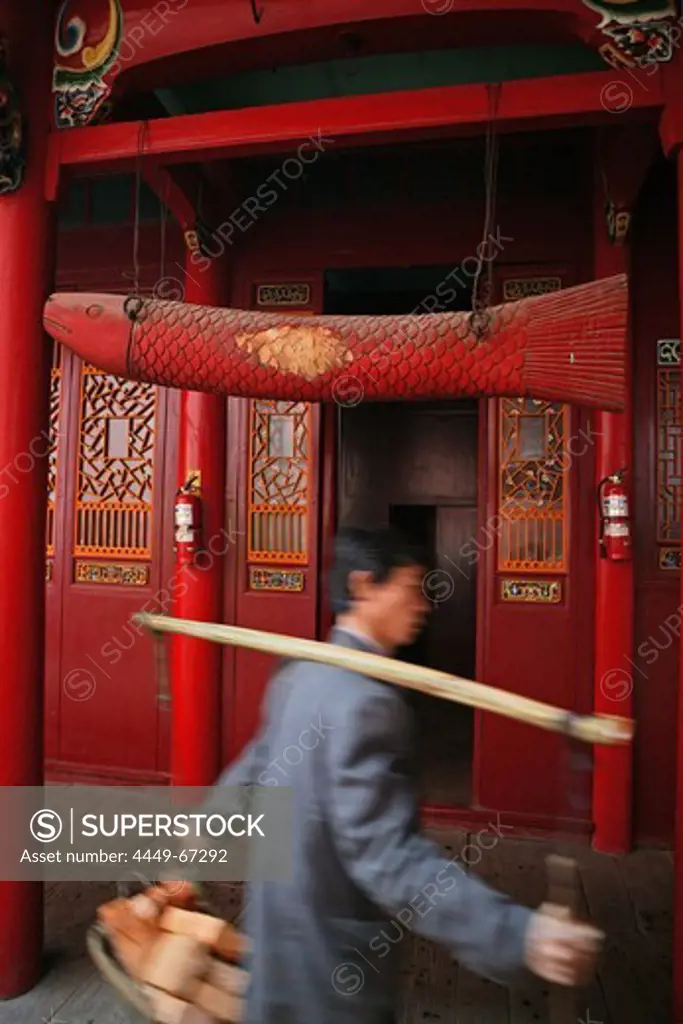 Porter with building material and wooden fish in front of Qiyuan monastery, Jiuhuashan, Anhui province, China, Asia