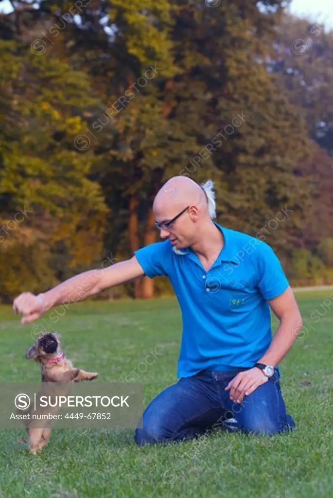 Man playing with dog, English Garden, Schwabing, Munich, Germany