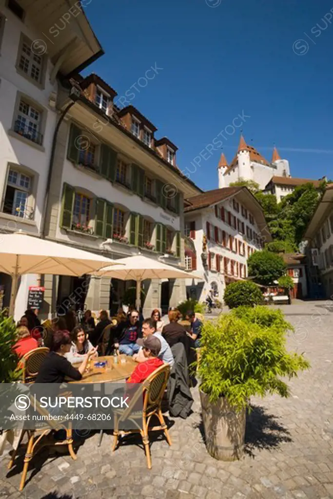 People sitting in pavement cafe of restaurant Ratsstuebli, Rathausplatz (town hall square), Castle Thun in background, Thun (largest garrison town of Switzerland), Bernese Oberland (highlands), Canton of Bern, Switzerland