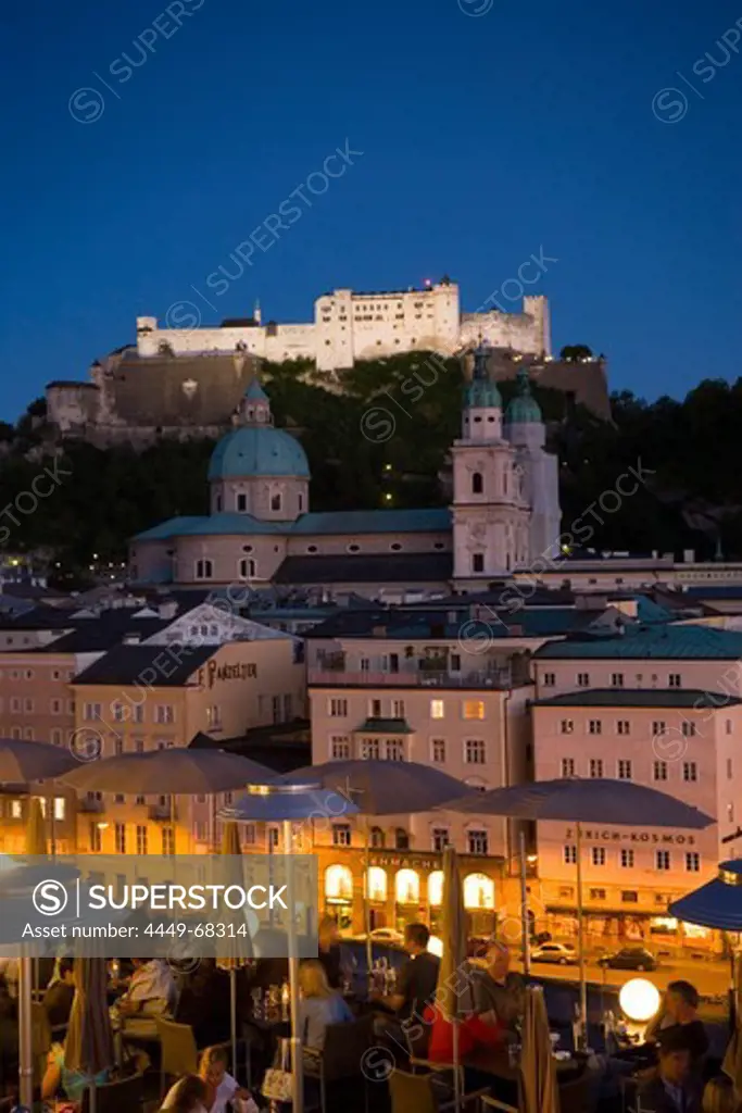 View over illuminated roof deck of restaurant Hotel Stein to old town with Salzburg Cathedral and Hohensalzburg Fortress, largest, fully-preserved fortress in central Europe, in the evening, Salzburg, Salzburg, Austria, Since 1996 historic centre of the city part of the UNESCO World Heritage Site