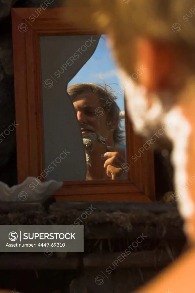 Reflection of a man shaving in a broken mirror, Madagascar, Africa