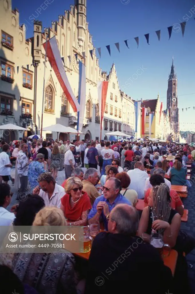 Festive crowd celebrating the Old Town feast surrounded by Gothic city hall and church tower of St Martin, Landshut, Lower Bavaria, Germany