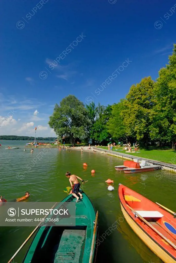 Two children fishing and rowing boats at beach of lake Simssee, Chiemgau, Upper Bavaria, Bavaria, Germany