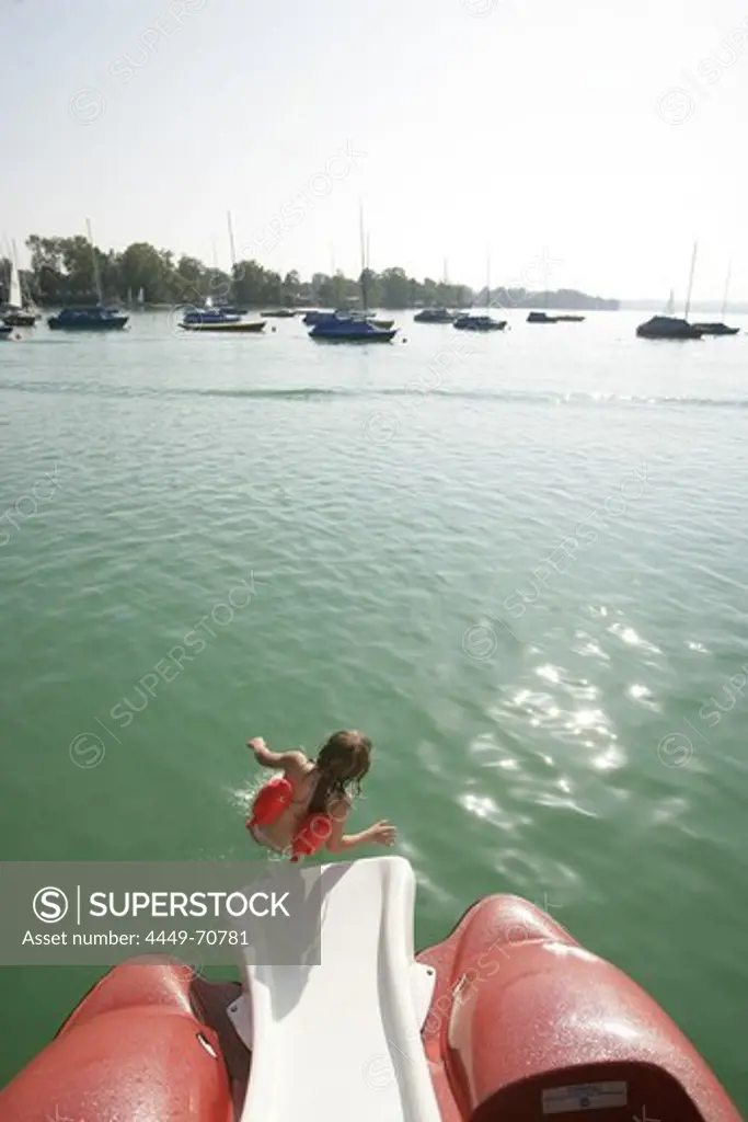 Child sliding down a slide on a paddleboat, Lake Woerthsee, Bavaria, Germany