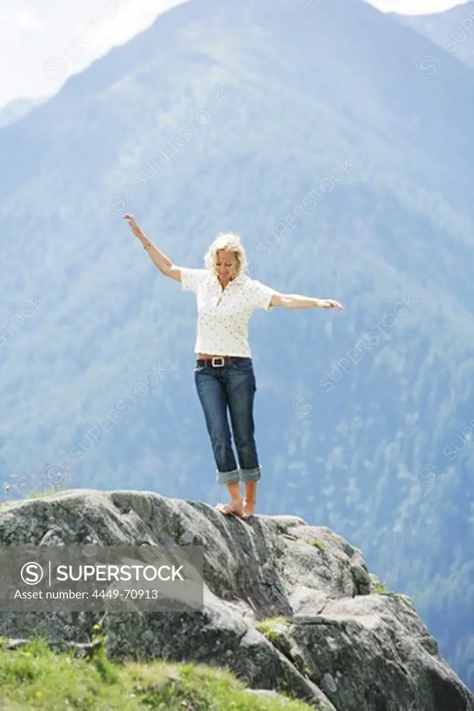 Barefoot woman balancing over rock, Heiligenblut, Hohe Tauern National Park, Carinthia, Austria